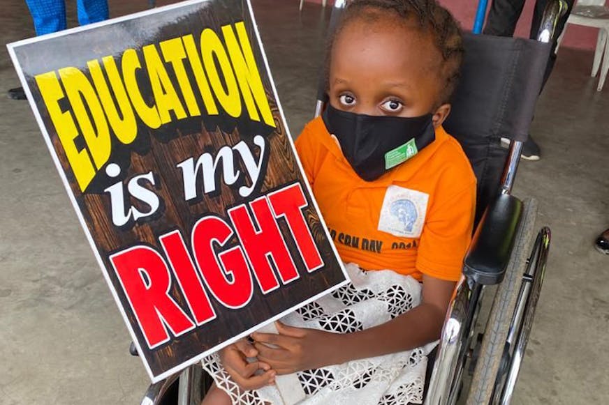 Meisje met handicap in nigeria houdt bord vast met Education is my Right