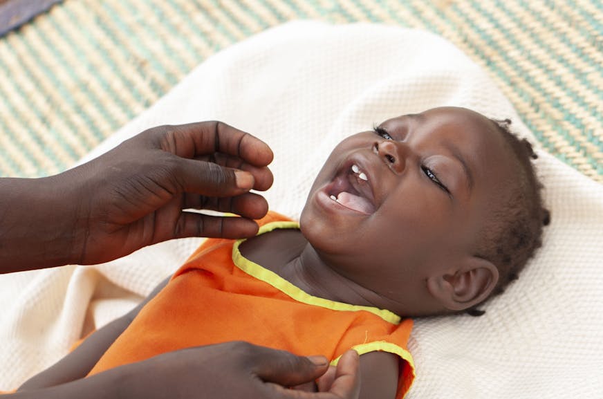 Agnes ligt op een kleedje en wordt liefedevol verzorgd door haar moeder Shamim.